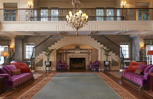 Reynolda House Reception Hall has a fireplace in the center of the back wall with staircases running up either side