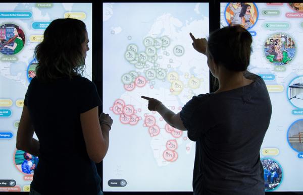 Two women touching screen that is showing a map